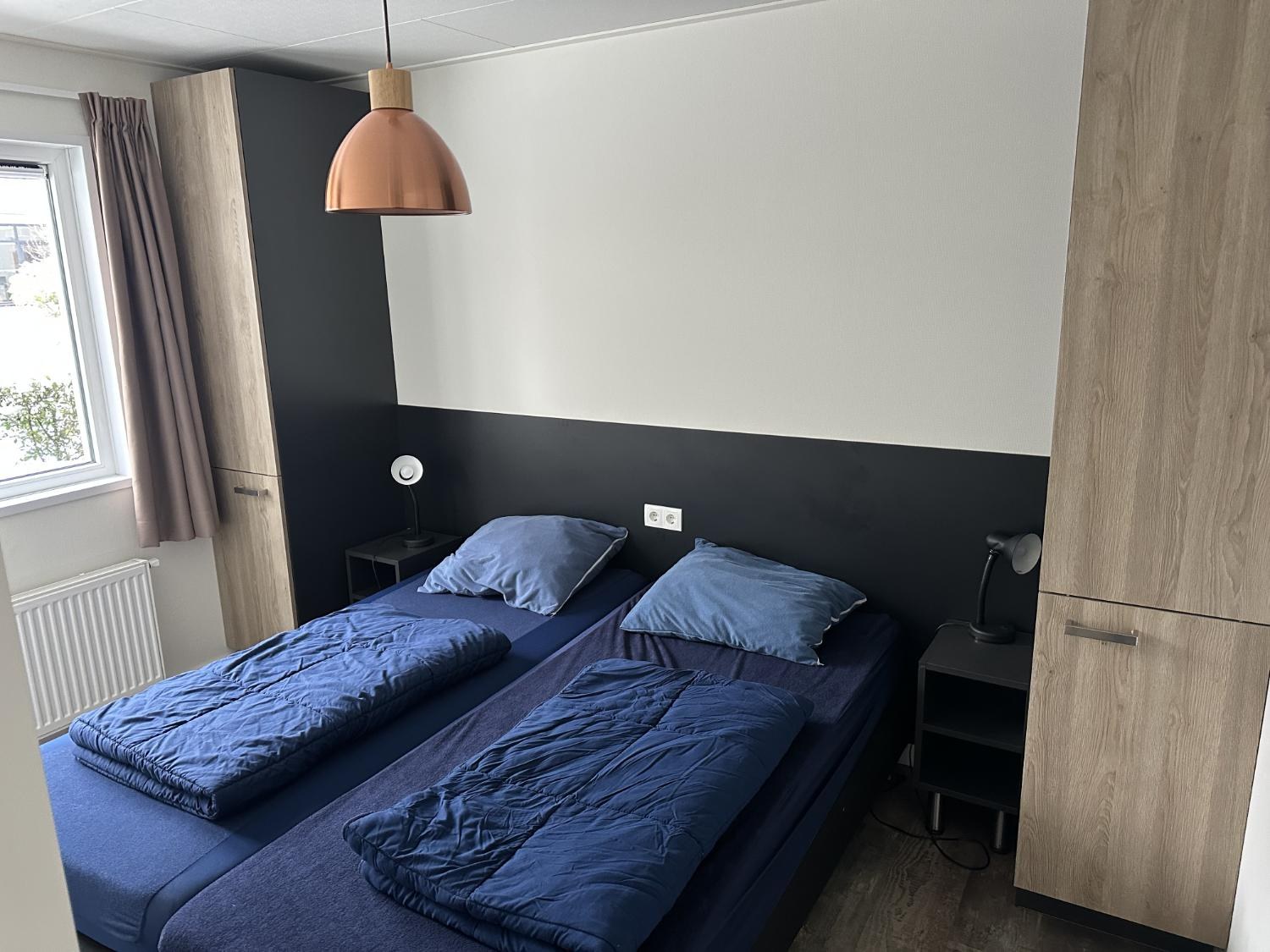 Slaapkamer met twee eenpersoonsbedden en kasten