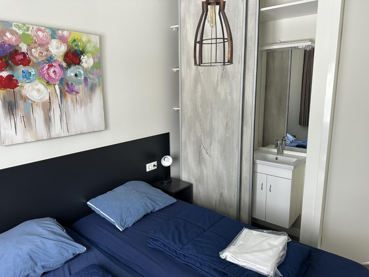 Slaapkamer met tweepersoonsbed en wastafel achter de schuifdeur