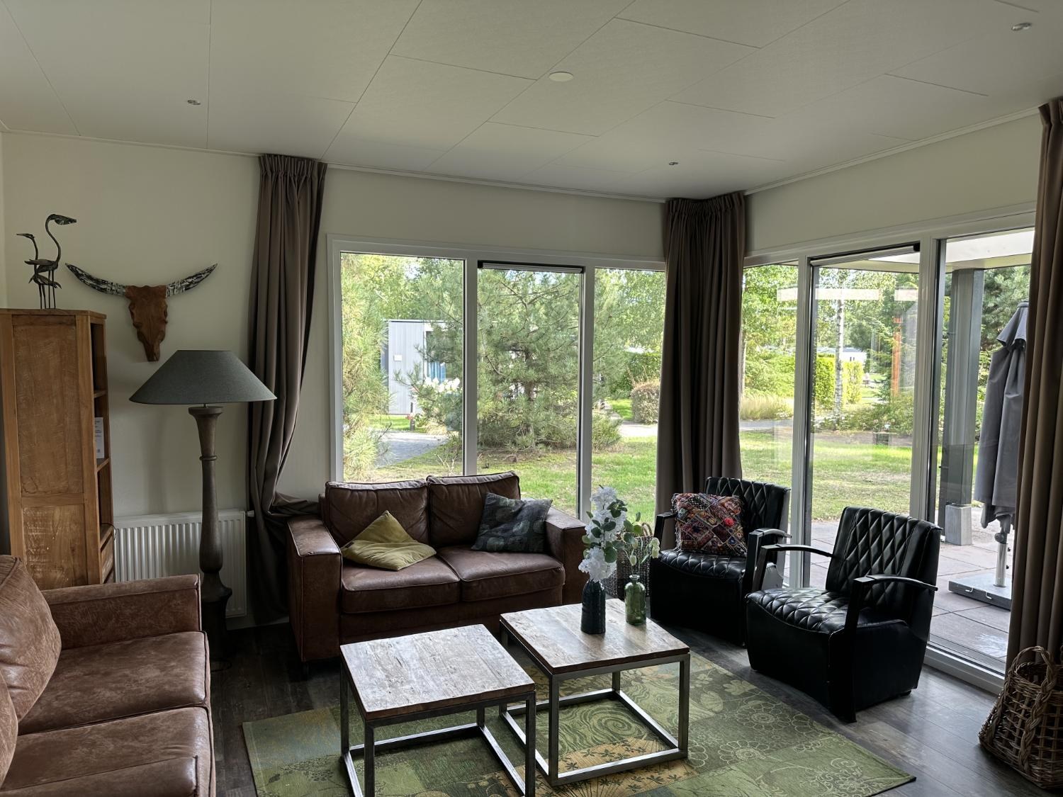 Woonkamer met leren banken, uitzicht op het gazon en de schuifpui naar het terras